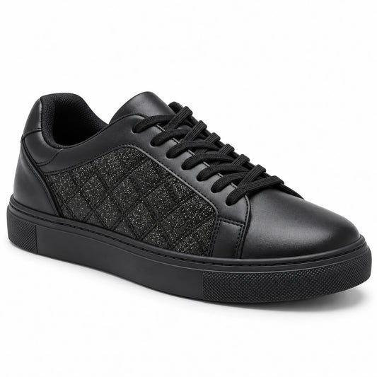 A black low-top sneaker with a quilted textured side panel, black laces, and a thick black sole, shown from a three-quarters angle on a white background.